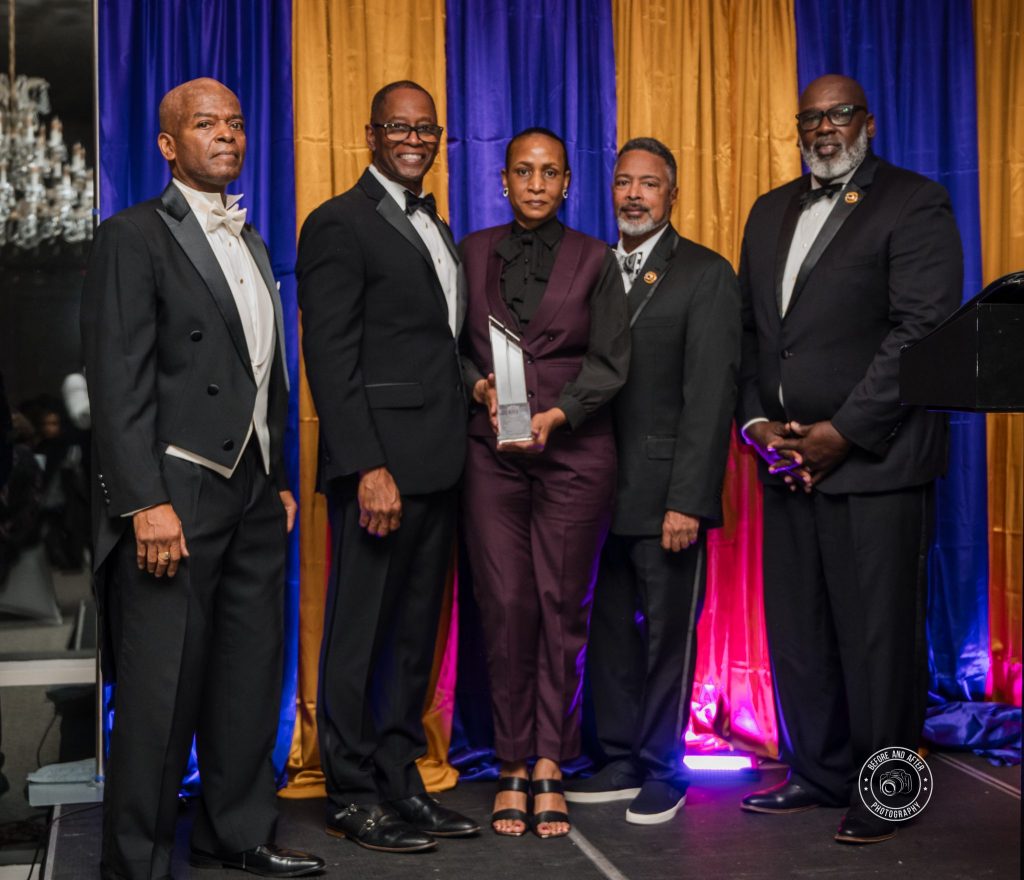 Lana Reid standing with members of the Eta Nu Nu Chapter of Omega Psi Phi Fraternity after receiving the 2025 Humanitarian Award.