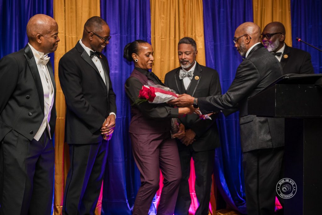 Lana Reid receiving roses during the 2025 Humanitarian Award presentation hosted by the Eta Nu Nu Chapter of Omega Psi Phi Fraternity.