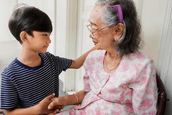 Young child sharing a warm moment with an elderly woman, illustrating how kindness, respect, and good manners are passed from one generation to the next.